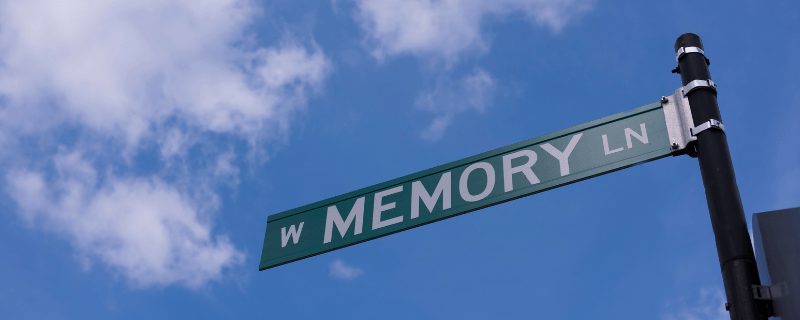 Memory Lane street sign against blue sky with white clouds.