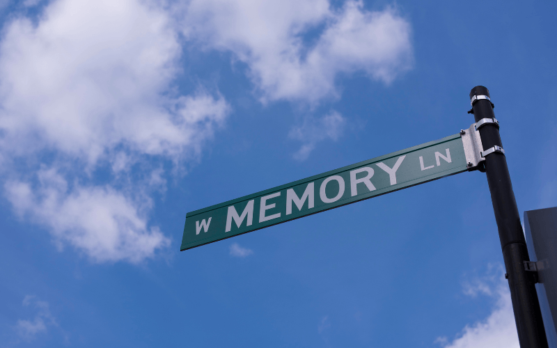 Memory Lane street sign against blue sky with white clouds.