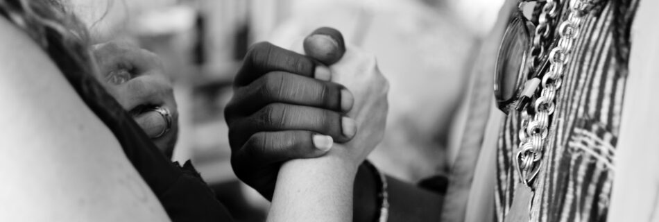 Black and white photograph of a unionized holding hands between a white female and and a black male persons.