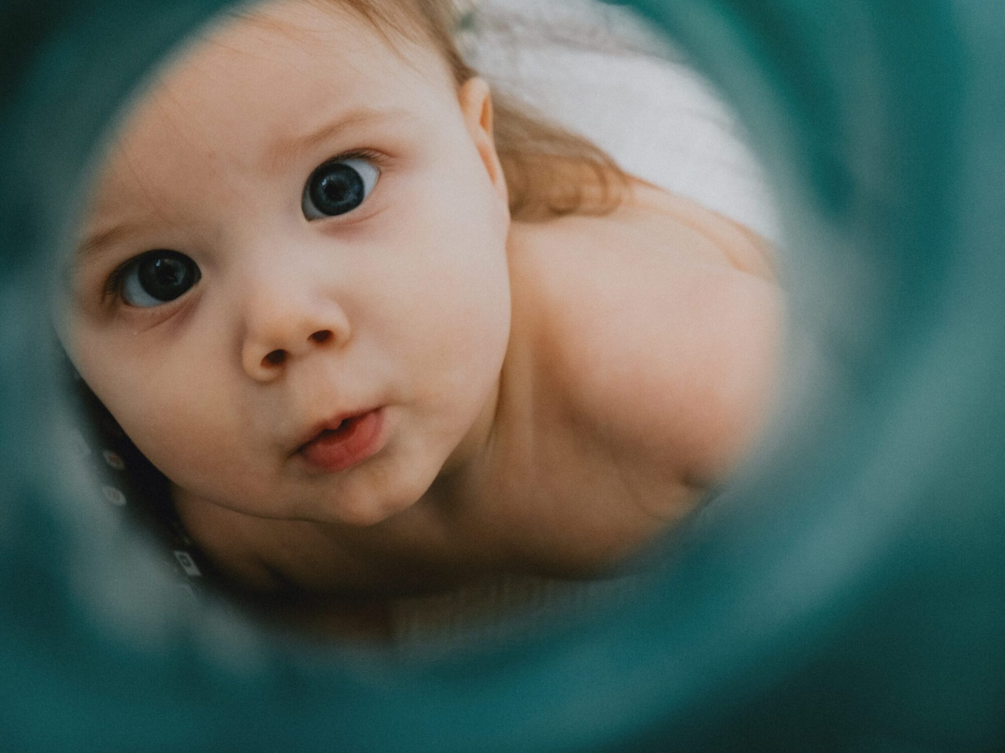 Baby is looking through the other end of the camera lense.